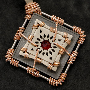 Detail view of 18K Rose Gold and 18K Palladium White Gold and Sterling Silver and Ruby Sewn Gold Metal Confidence pendant featuring 4 pointed gear by Caps Brothers