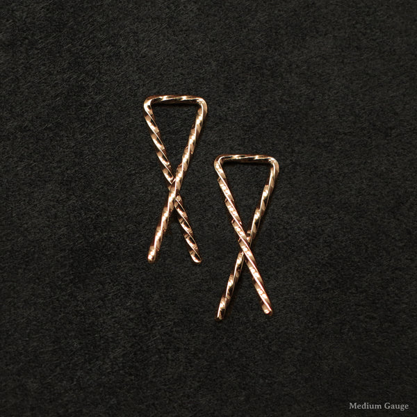 Laying down pair of 18K Rose Gold Sibling Ribbons Twisted Earrings representing we are all brothers and sisters by Caps Brothers