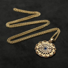 Load image into Gallery viewer, Laying down view of 18K Yellow Gold and 18K Palladium White Gold and Sapphire Sewn Gold Metal Majesty pendant and chain with endless loop necklace featuring 20 pointed gear by Caps Brothers