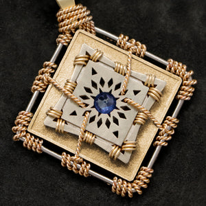 Detail view of 18K Yellow Gold and 18K Palladium White Gold and Sapphire Sewn Gold Metal Confidence pendant featuring 4 pointed gear by Caps Brothers