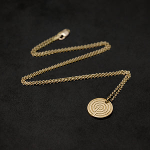 Laying down 18K Yellow Gold Journey pendant and chain necklace with clasp featuring labyrinth as inward journey by Caps Brothers