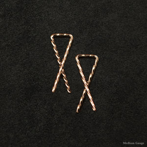Laying down pair of 18K Rose Gold Sibling Ribbons Twisted Earrings representing we are all brothers and sisters by Caps Brothers