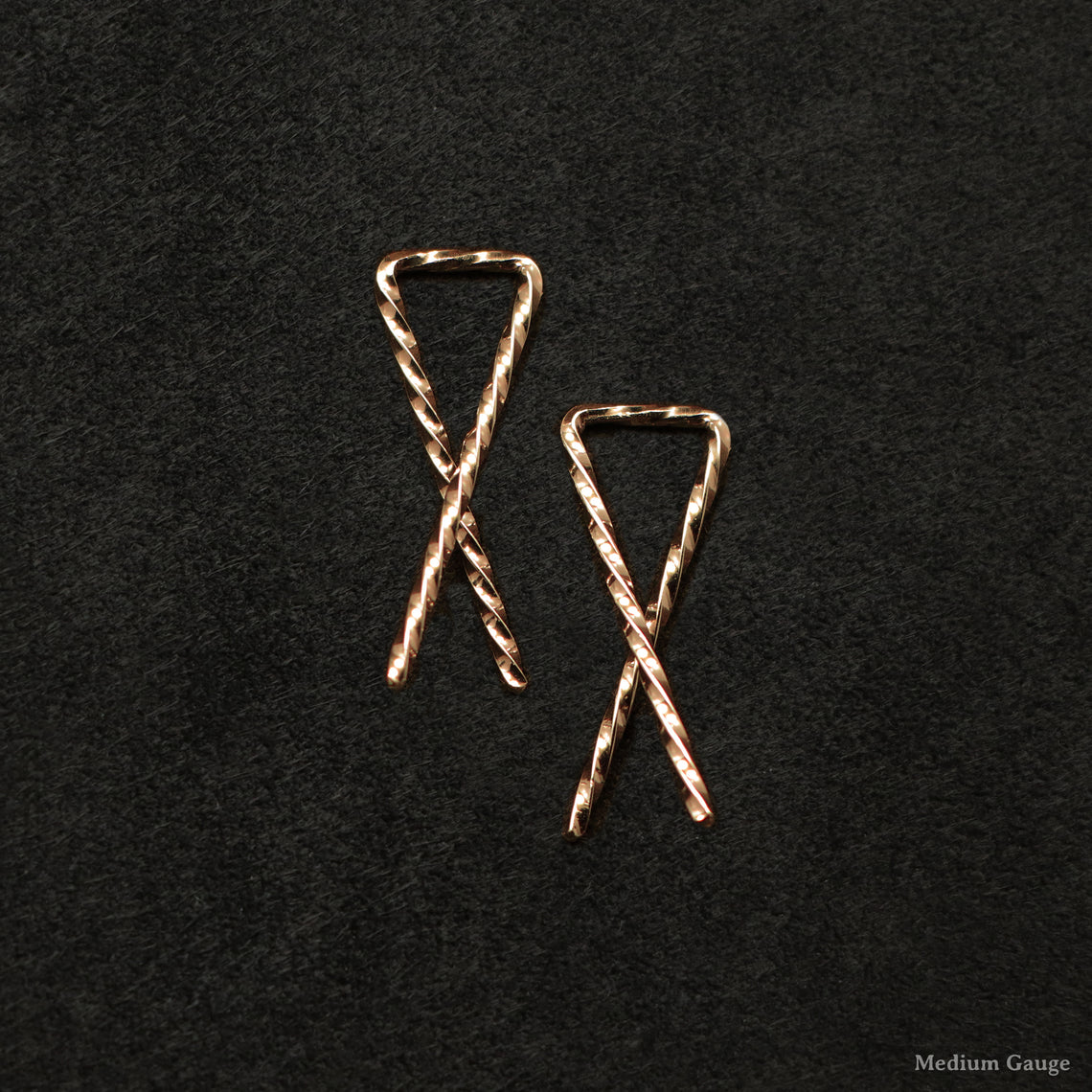 Laying down pair of 18K Rose Gold Sibling Ribbons Twisted Earrings representing we are all brothers and sisters by Caps Brothers