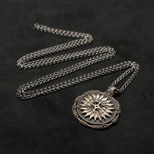 Load image into Gallery viewer, Laying down view of 18K Palladium White Gold and Sterling Silver Sewn Gold Metal Compass pendant and chain with endless loop necklace featuring 20 pointed gear by Caps Brothers