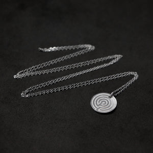 Laying down Platinum 950 Journey pendant and chain with endless loop necklace featuring labyrinth as inward journey by Caps Brothers