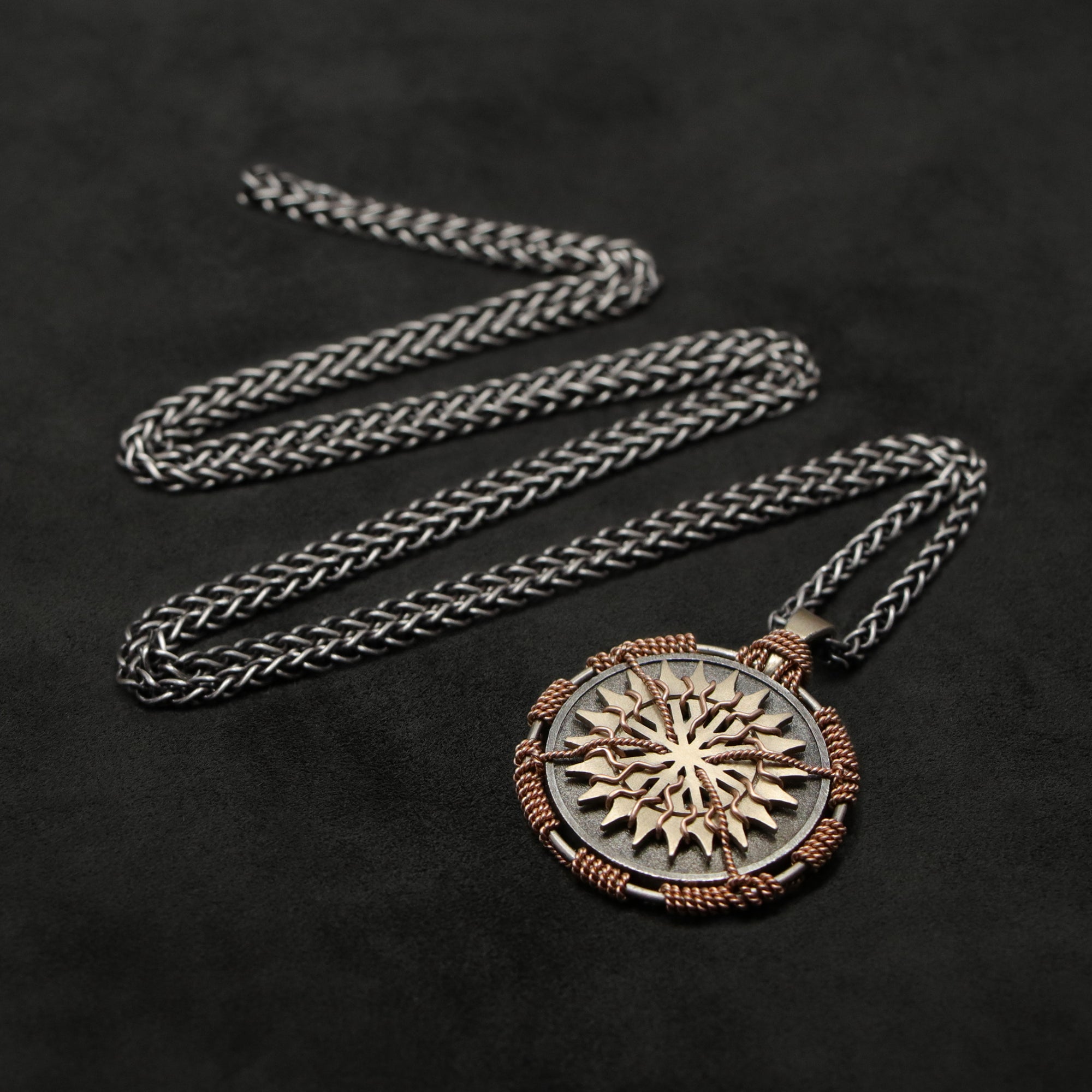 Laying down view of 18K Rose Gold and 18K Palladium White Gold and Sterling Silver Sewn Silver Metal Sun pendant and chain with endless loop necklace featuring 20 pointed gear by Caps Brothers